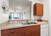 Thumbnail 9 of 71 - A kitchen with a white dishwasher and brown cabinets.