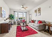 Thumbnail 12 of 71 - A living room with a grey couch, a red rug, and a ceiling fan.