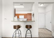 Thumbnail 11 of 71 - A kitchen with white walls and a counter with two stools.