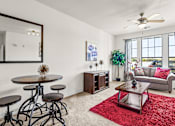 Thumbnail 13 of 71 - A living room with a round table and a red rug.