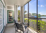 Thumbnail 18 of 71 - A balcony with a chair and a table overlooking a body of water.