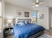 Thumbnail 40 of 46 - A bedroom with a blue bedspread and a ceiling fan.