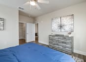 Thumbnail 41 of 46 - A bedroom with a blue bedspread and a ceiling fan.