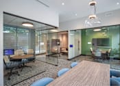 Thumbnail 20 of 44 - A modern office space with glass walls and a wooden table.