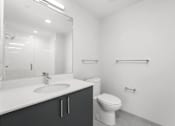 Thumbnail 44 of 44 - A white bathroom with a toilet, sink, and mirror.