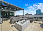 Thumbnail 4 of 44 - A modern outdoor living space with a large grey sofa and a glass coffee table.