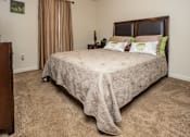 Thumbnail 6 of 19 - A bedroom with a large bed and a carpeted floor.