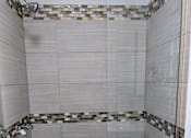 Thumbnail 10 of 19 - A shower area with a tiled floor and walls.