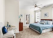 Thumbnail 27 of 71 - A bedroom with a bed, chair, and ceiling fan.