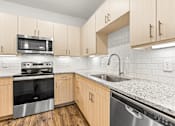 Thumbnail 23 of 50 - A kitchen with wooden cabinets and a granite countertop.