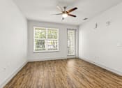 Thumbnail 25 of 50 - A room with a ceiling fan and wooden flooring.