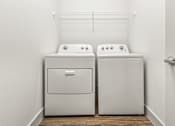 Thumbnail 29 of 50 - Two white front loading washing machines in a laundry room.