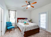 Thumbnail 38 of 71 - A bedroom with a bed, chair, and ceiling fan.