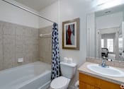 Thumbnail 37 of 71 - A bathroom with a white toilet, a white sink, a white bathtub, and a shower curtain.