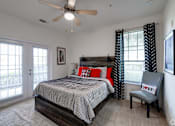 Thumbnail 42 of 71 - A bedroom with a bed, chair, and ceiling fan.