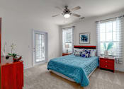 Thumbnail 47 of 71 - A bedroom with a blue bedspread and a ceiling fan.