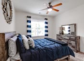 Thumbnail 45 of 71 - A bedroom with a bed, dresser, mirror, and a ceiling fan.