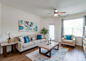 Thumbnail 34 of 71 - A living room with a beige couch, a coffee table, and a ceiling fan.