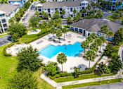 Thumbnail 38 of 44 - An aerial view of a swimming pool surrounded by palm trees and a building.