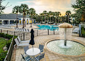 Thumbnail 5 of 71 - A pool area with a fountain, chairs, and umbrellas.