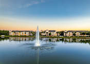 Thumbnail 2 of 71 - A fountain in the middle of a lake with buildings in the background.