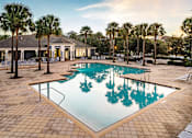 Thumbnail 6 of 71 - A pool surrounded by palm trees and a building in the background.