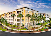 Thumbnail 32 of 50 - A large apartment complex with a parking lot in front.