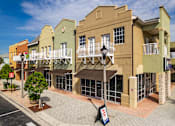 Thumbnail 48 of 50 - A street view of a row of colorful buildings with balconies and a tree in a planter.