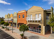 Thumbnail 44 of 50 - A street view of a row of colorful buildings with a clear blue sky above.