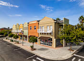 Thumbnail 49 of 50 - A street view of a row of colorful buildings with a clear blue sky above.
