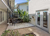 Thumbnail 9 of 12 - A patio area with a bench, plants, and a door.
