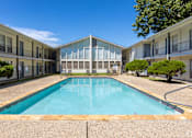 Thumbnail 1 of 12 - A swimming pool in a courtyard surrounded by buildings.