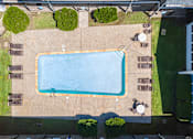 Thumbnail 6 of 12 - An aerial view of a swimming pool surrounded by a concrete patio and a grassy area.