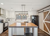 Thumbnail 20 of 23 - A modern kitchen with a wooden island in the center.