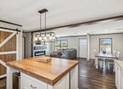 Thumbnail 21 of 23 - A kitchen with a wooden island and a dining table with chairs.