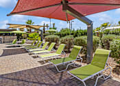 Thumbnail 15 of 23 - Poolside loungers with sun shades at Verde Plaza Manufactured Home Community in Tucson, Arizona
