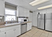 Thumbnail 21 of 23 - A kitchen with white cabinets and appliances.