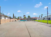Thumbnail 14 of 23 - A tennis court surrounded by a fence and a flag on a pole.