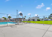 Thumbnail 13 of 23 - A basketball court with a basketball hoop and a pool in the background.