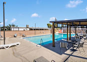 Thumbnail 10 of 23 - A pool with chairs and a building in the background.