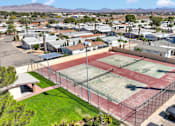 Thumbnail 7 of 23 - A tennis court is surrounded by a fence and a parking lot.