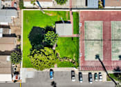 Thumbnail 6 of 23 - A tennis court is surrounded by a grassy area and a parking lot.