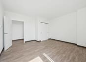 Thumbnail 17 of 45 - A room with white walls and wooden flooring with a rug in the middle.