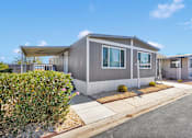 Thumbnail 1 of 23 - A grey house with a white fence and bushes in front.