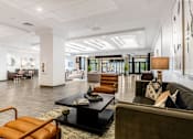 Thumbnail 9 of 45 - A modern living room with a black coffee table and a brown leather chair.