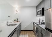 Thumbnail 40 of 45 - A modern kitchen with stainless steel appliances and a white countertop.