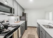 Thumbnail 44 of 45 - A kitchen with a black stove top oven and a black microwave above it.