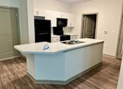 Thumbnail 10 of 21 - A kitchen with a white counter and a black fridge.at Arbours at Moores Mill, Huntsville, AL 35811