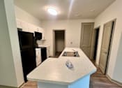 Thumbnail 17 of 21 - A kitchen with a black fridge and microwave, a white island, and a sink.at Arbours at Moores Mill, Huntsville