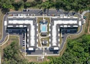 Thumbnail 1 of 20 - An aerial view of a parking lot and buildings with a pool in the middle.